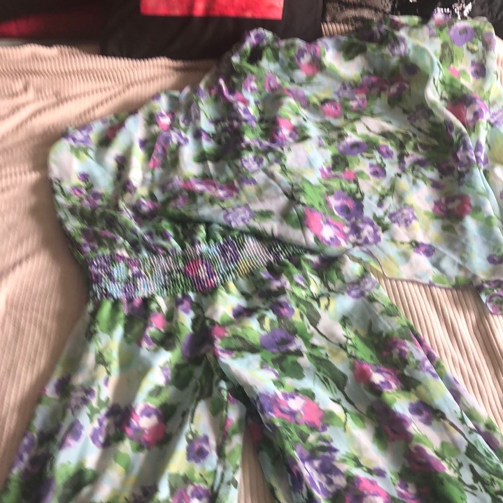 This is a floral jumpsuit with a scarf attached to the top of it on one side.